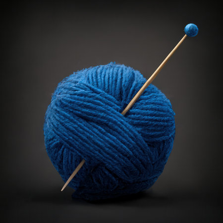 Generative AI illustration of blue woolen yarn ball with needle on black backgroundの素材