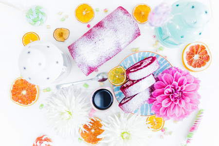 A red velvet cake roll sliced with cup of coffee flowers and candy, dried oranges. Top view.の写真素材