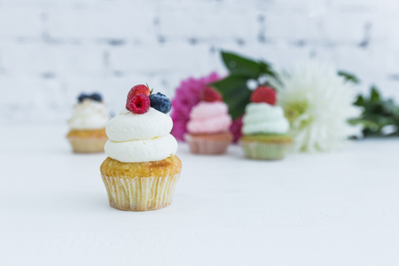 Various cupcakes with fresh berries flowers and leaves.の写真素材