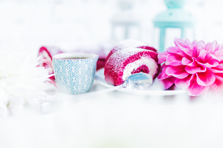 A red velvet cake roll sliced with cup of coffee or tea and flowers.の写真素材