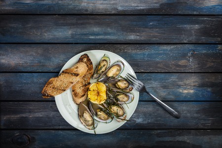 Mussels and bread toasts on on a white plate. Top viewの写真素材