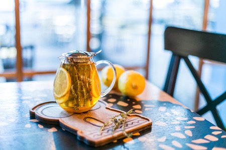 Cup of herbal tea with thyme and lemon served with board on the table.の写真素材
