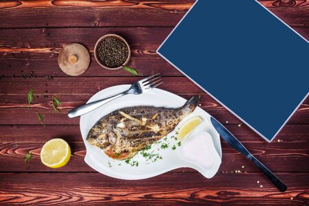 Grilled Dorado on a plate. Healthy food. There is a black pepper and cutlery and a place for text. Top view on a wooden background.の写真素材