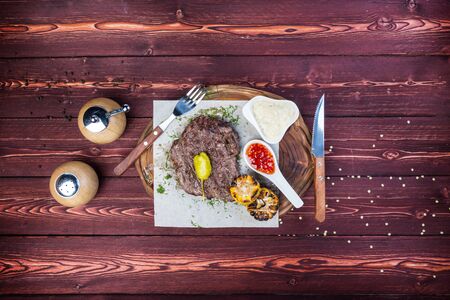 Delicious grilled steak with sauces and fried corn. There is a cutlery. Top view on a wooden background.の写真素材