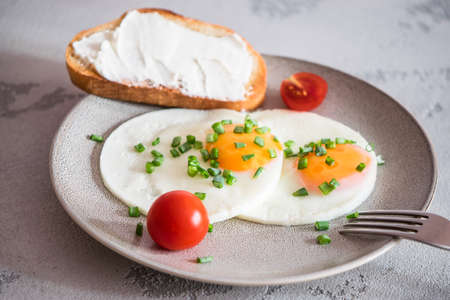 fried eggs with tomatoes, green onions and toastの写真素材
