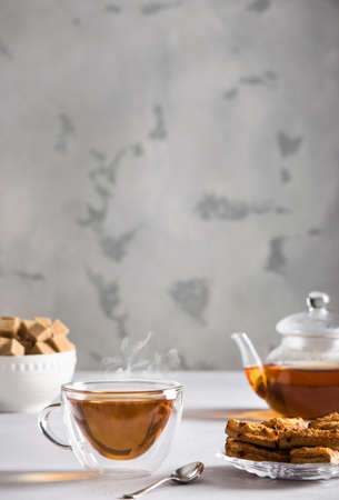 teapot and cup with steaming hot tea, cookies and sugarの写真素材