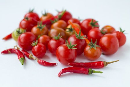 Cherry tomatoes and red hot chili peppers on a white background.の写真素材