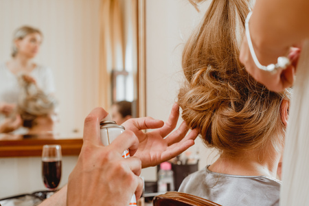 Master stylist makes the bride wedding hairstyle using spray lacquer fixing. Hairdresser at work. close-upの写真素材