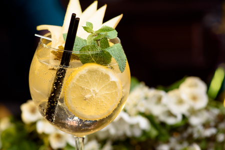 yellow summer cocktail decorated with mint, lemon and slices pears on a wooden table on a floral background. close upの写真素材