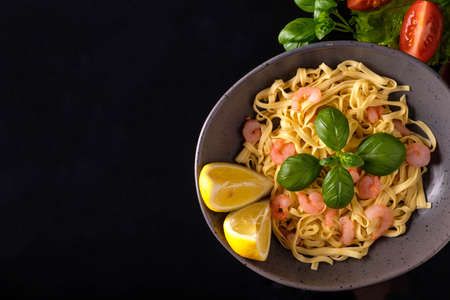 Pasta with shrimps, basil and tomatoes on a dark background. View from aboveの写真素材