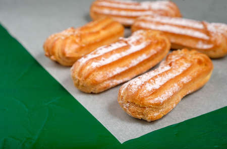 Eclairs on green background. Delicious French dessert. Sweet dessert. Full depth of field.