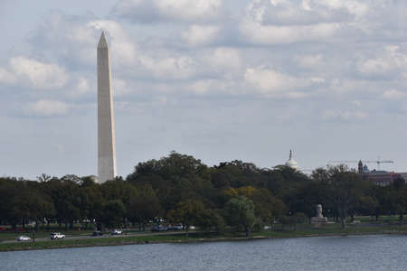 Washington, DC, USA - October 25, 2021: The Washington Monument and the Top of the Rotunda of the U.S. Capitol Peak Over the Tree Line as Seen from Across the Potomac Riverのeditorial素材