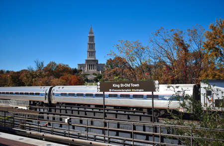 Alexandria, Virginia, USA - November 1, 2021: King Street  - Old Town WMATA Metro Station, looking at the George Washington Masonic Temple, with an Amtrak Train in the Foreground on a Fall Afternoonのeditorial素材