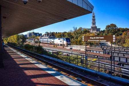 Alexandria, Virginia, USA - November 1, 2021: King Street  - Old Town WMATA Metro Station, looking at the George Washington Masonic Temple, with an Amtrak Train in the Foreground on a Fall Afternoonのeditorial素材