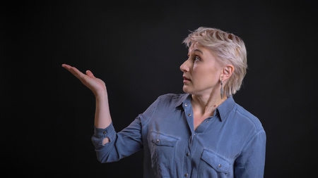 Closeup portrait of adult attractive caucasian female demonstrating a presentation with her hand pointing on the sideの写真素材