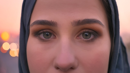 Closeup shoot of young attractive female face in hijab with gray eyes looking straight at camera...