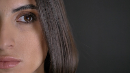Close-up half-portrait of young pretty long-haired girl in plaided shirt watching seriously leftwards on black background.の写真素材