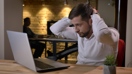Closeup shoot of adult caucasian hurrying businessman typing on the laptop being busy and stressed to meet deadlines indoors in the officeの写真素材