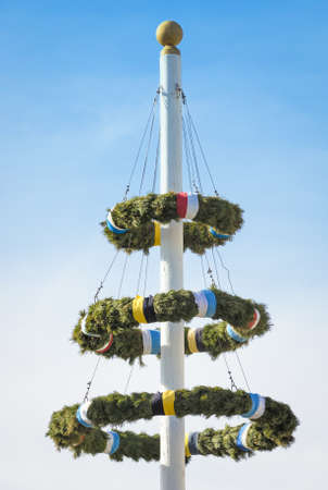 typical bavarian maypole in front of blue skyの写真素材