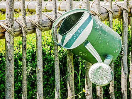 old watering can at a fenceの写真素材