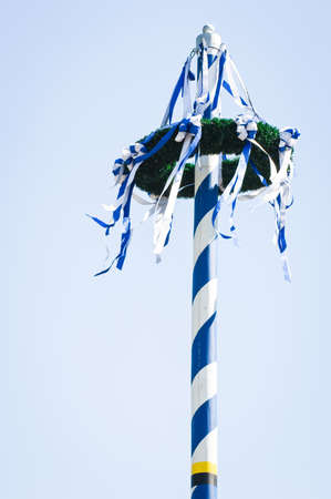 typical bavarian maypole in front of blue skyの写真素材