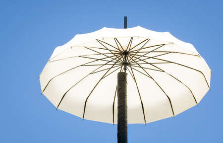 old-fashioned white parasol in front of blue skyの写真素材