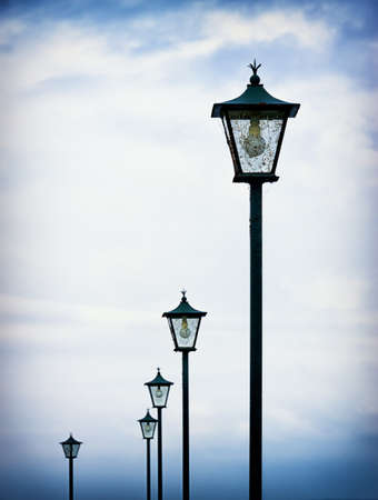beautiful old streetlamps in front of blue skyの写真素材