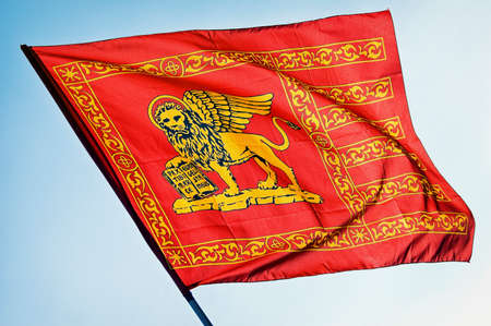 the flag of venice/italy in front of blue sky