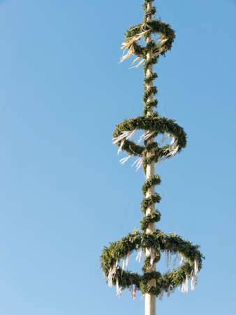 typical bavarian maypole in front of blue skyの写真素材