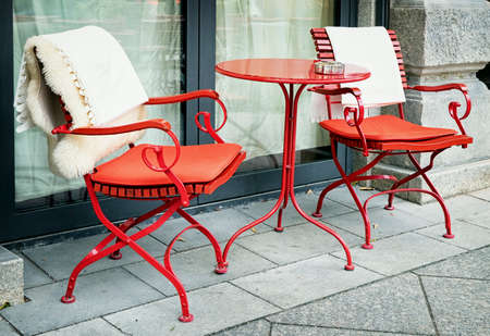 red table and chairs at a sidewalkの写真素材