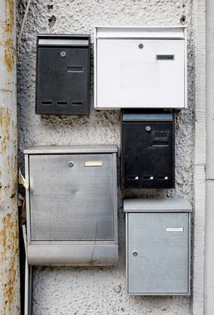 five old letterboxes at a wall