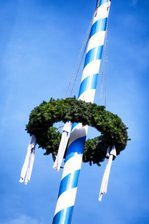 typical bavarian maypole in front of blue skyの写真素材