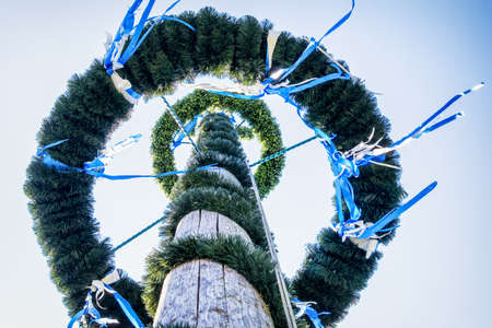 typical bavarian maypole in front of blue skyの写真素材