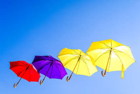 flying umbrellas in front of blue skyの写真素材