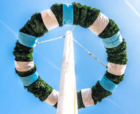 typical bavarian maypole in front of blue skyの写真素材