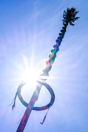typical bavarian maypole in front of blue skyの写真素材