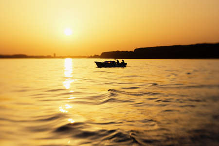 Small boat on river in sunsetの写真素材