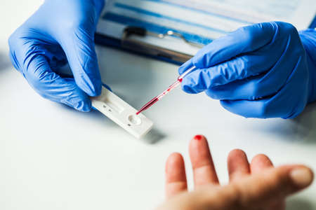 Coronavirus COVID-19 quick Rapid Diagnostic Test RDT,medical worker place collected patient finger...