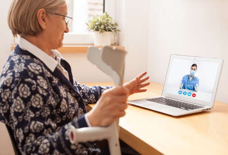 Retired senior elderly woman talking to GP female doctor via virtual telemedicine video...