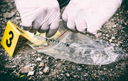 Crime scene investigation, picking up the tossed syringe and putting it to the plastic bagの写真素材