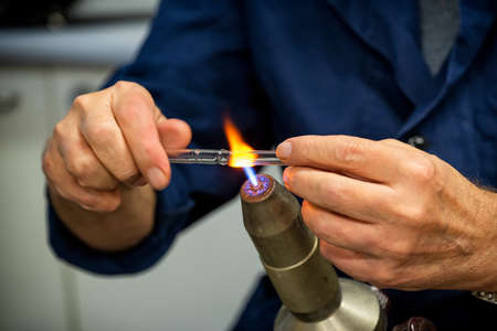Glass blower forming a chemistry glass, closeup view, glass blower using a glassblowing torchの写真素材