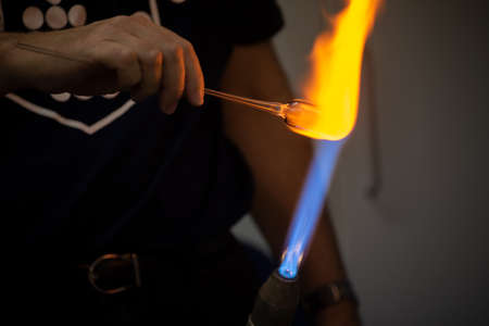 Glass blower forming a chemistry glass, closeup view, glass blower using a glassblowing torchの写真素材