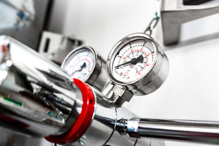 Closeup of pressure manometer measuring gas pressure, industry background, selective focus, pipes and valves in the chemistry laboratoryの写真素材