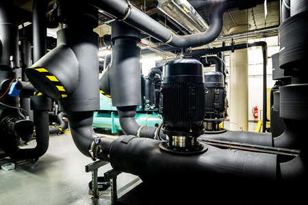 Pump station in the underground premises of the factory, heat station and water treatment facility, pumps and valves, black pipelinesの写真素材