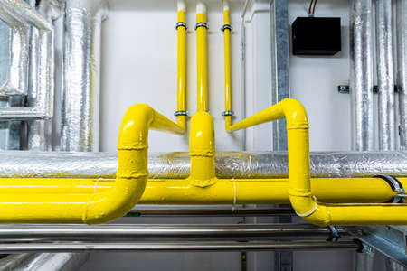 Gas and waste pipelines in the underground premises of the factory, industrial background, building utilitiesの写真素材