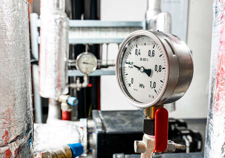 Barometers on pressure pipes, underground premises of the factory with heat and water distribution...