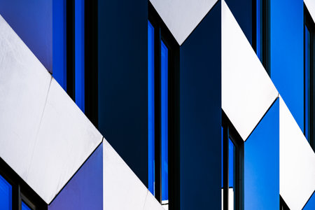 Abstract Close-Up of Modern Building Facade with Angular Patterns and Reflective Blue Windowsの写真素材