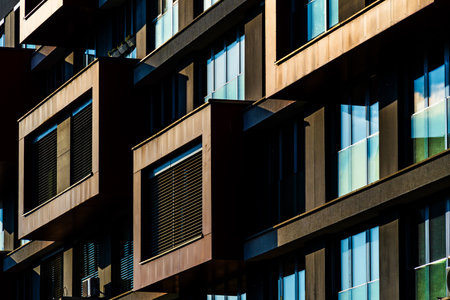 Modern Architectural Facade with Geometric Protrusions and Reflective Windows in Sunlightの写真素材