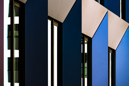 Abstract Close-Up of Modern Building Facade with Angular Patterns and Reflective Blue Windowsの写真素材