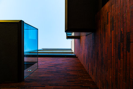 Abstract Architectural Perspective with Red Brick Walls, Glass Details, and Open Skyの写真素材